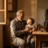 Cena emotiva de uma família em uma cozinha rústica, com avô, pai e filho, destacando o amor e a conexão familiar em um ambiente acolhedor.